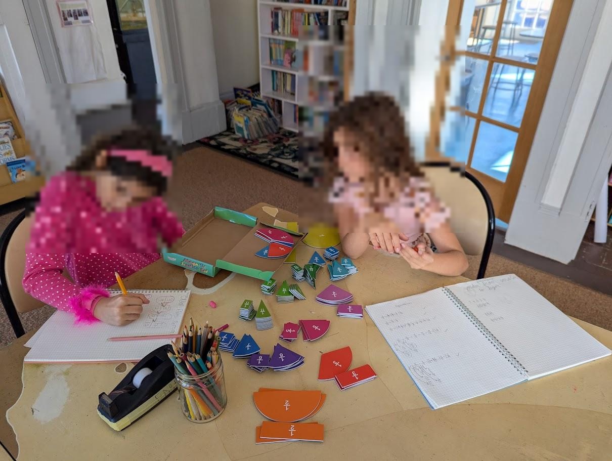 Two children working collaboratively with colorful fraction pieces