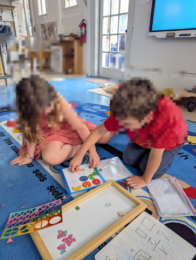 Two children side by side on the floor, both working on the same set of materials