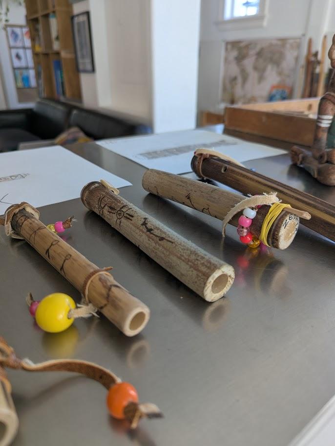 Finished bamboo flutes of different lengths displayed together, alongside natural objects