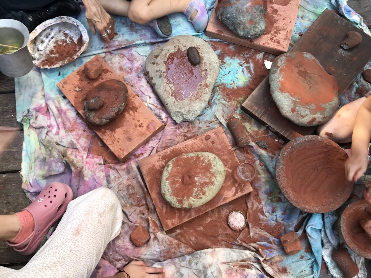 Top-down view of finished decorated adobe tiles arranged together — geometric patterns and organic shapes painted with natural pigments