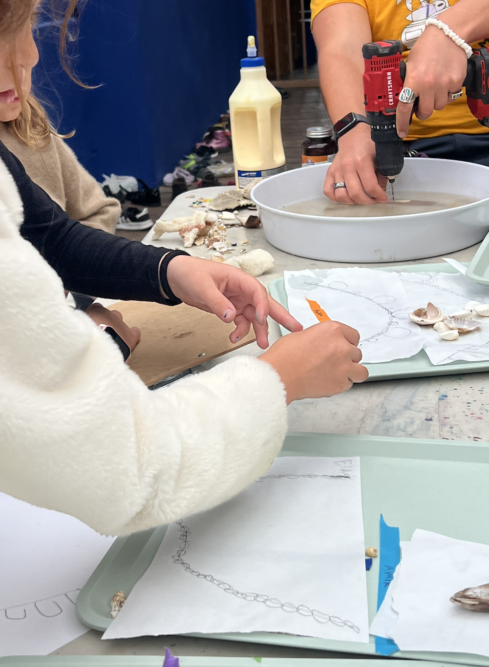 Hands carefully working with a shell — polishing or threading — as part of jewelry-making