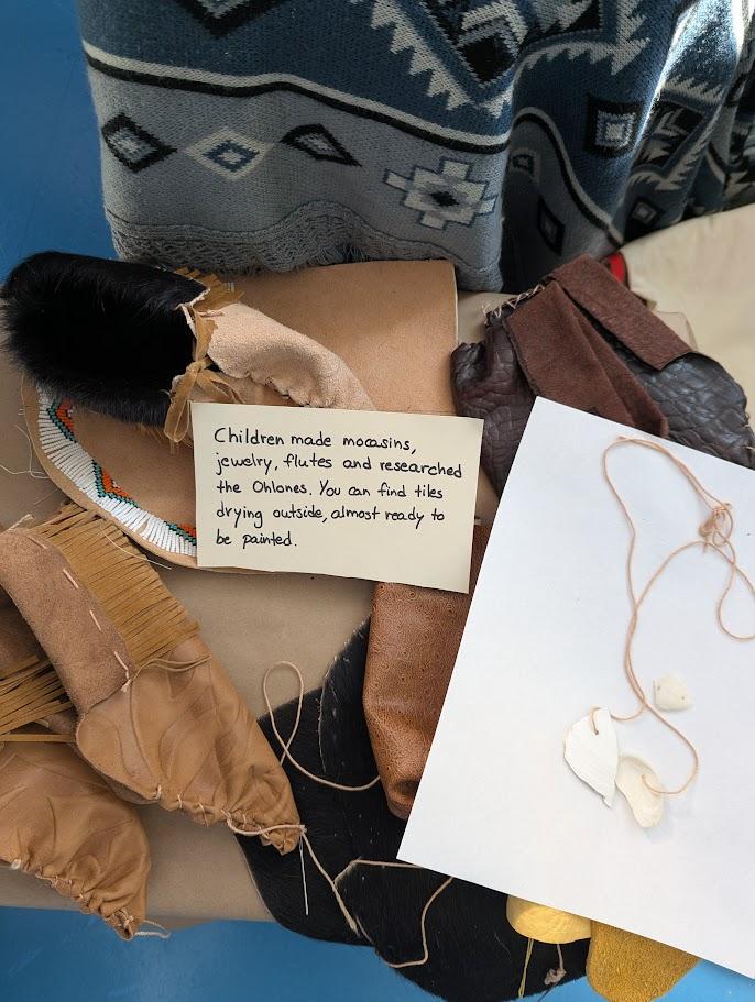 Moccasins, leather pieces, shell jewelry and a handwritten note about children's projects