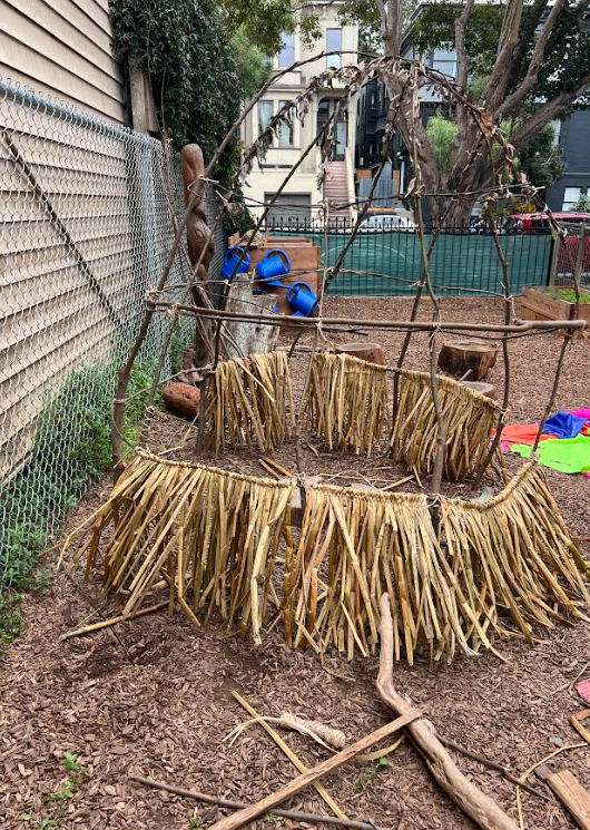 Children adding tule reeds to the frame — the house taking shape